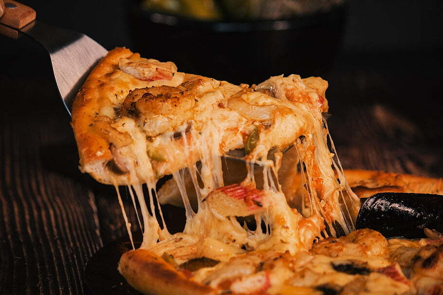 1. A hand holding a pizza topped with melted cheese and various seafood ingredients.